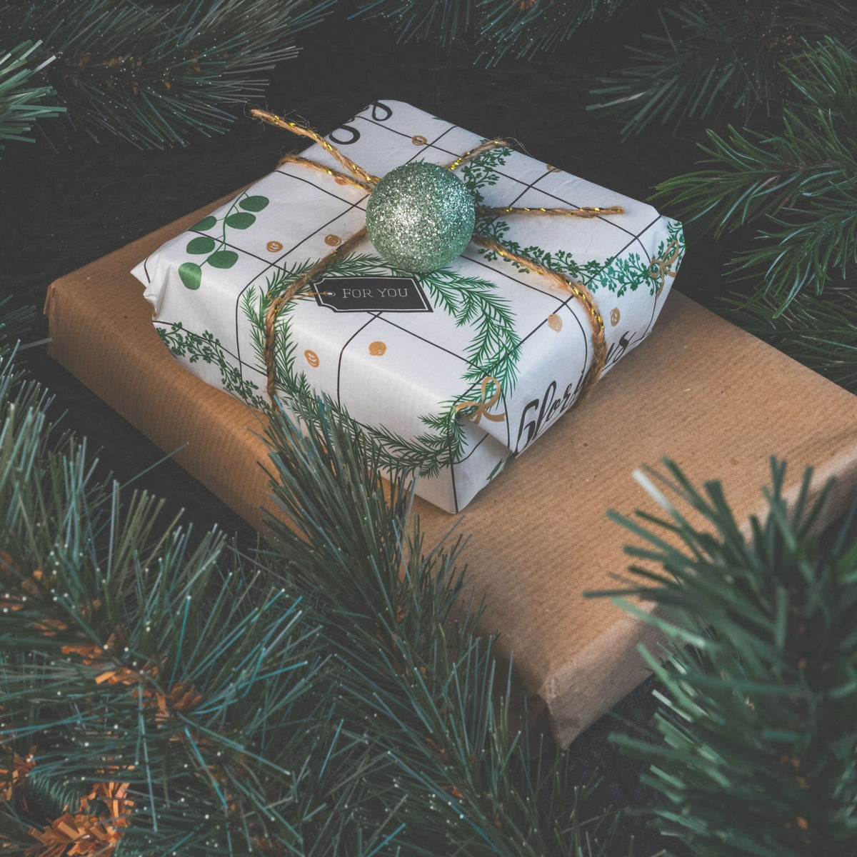Cadeau gourmand emballé pour Noël entre des branches de sapin